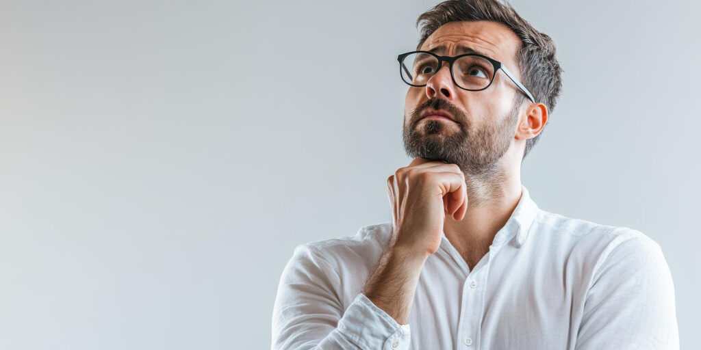 Hombre con gafas y camisa blanca en actitud pensativa